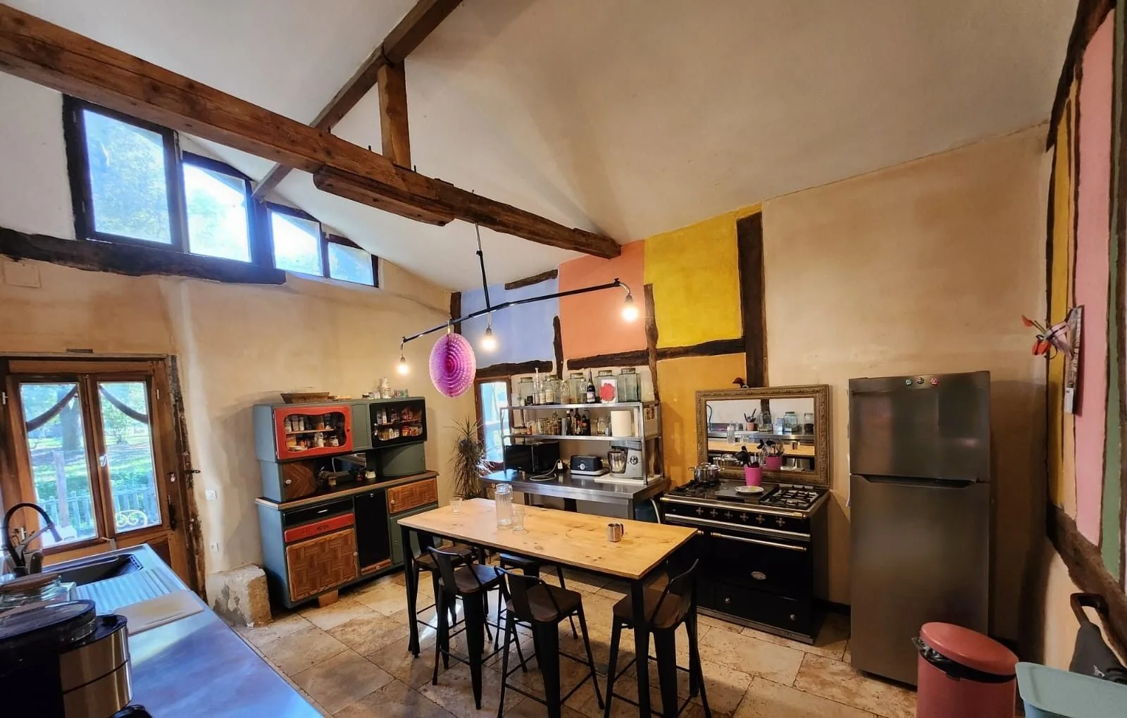 High-ceilinged kitchen with exposed beams and central table
